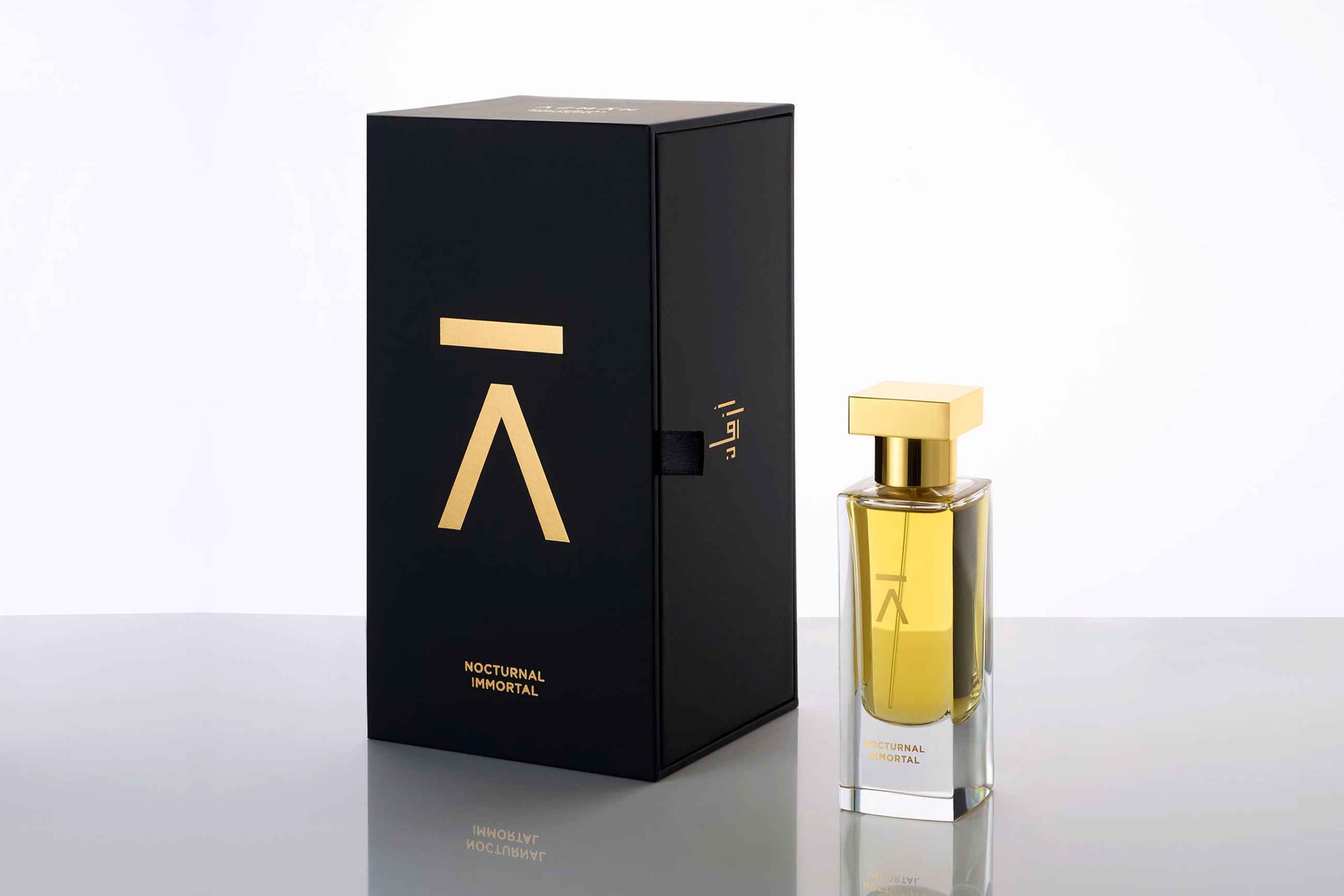 Studio photograph of the ‘Nocturnal Immortal’ perfume bottle and box by Azman Perfumes, created in collaboration with Julien Rasquinet. Set against a white background, the bottle reflects a woody, oriental, and mysterious aesthetic. The perfume features key notes of Fir Balsam Absolute, Orange Bitter Oil, Cistus Labdanum, Vetiver Oil Haiti, and Hay Absolute, embodying a rich and natural essence.