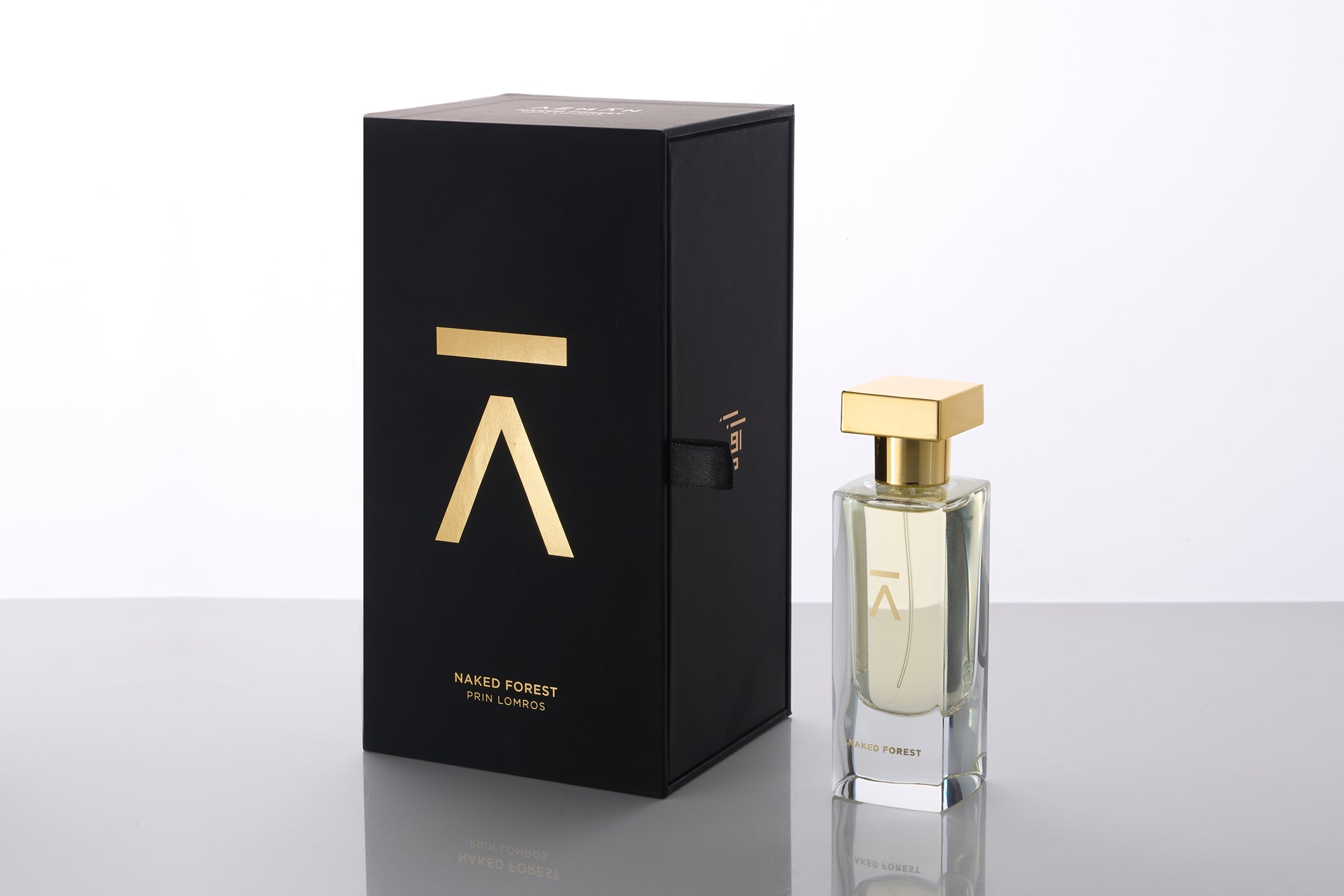 Studio photograph of a ‘Naked Forest’ perfume bottle by Azman Perfumes in collaboration with Prin Lomros, set against a white background. The bottle reflects a green, veggie, and mysterious aesthetic, highlighting elements such as iris, sandalwood, and mango.