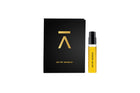 A small clear spray bottle filled with bright yellow liquid stands beside a tall black rectangular box with a gold geometric logo and the text 'OH MY SHIMSAI' on a plain white background.