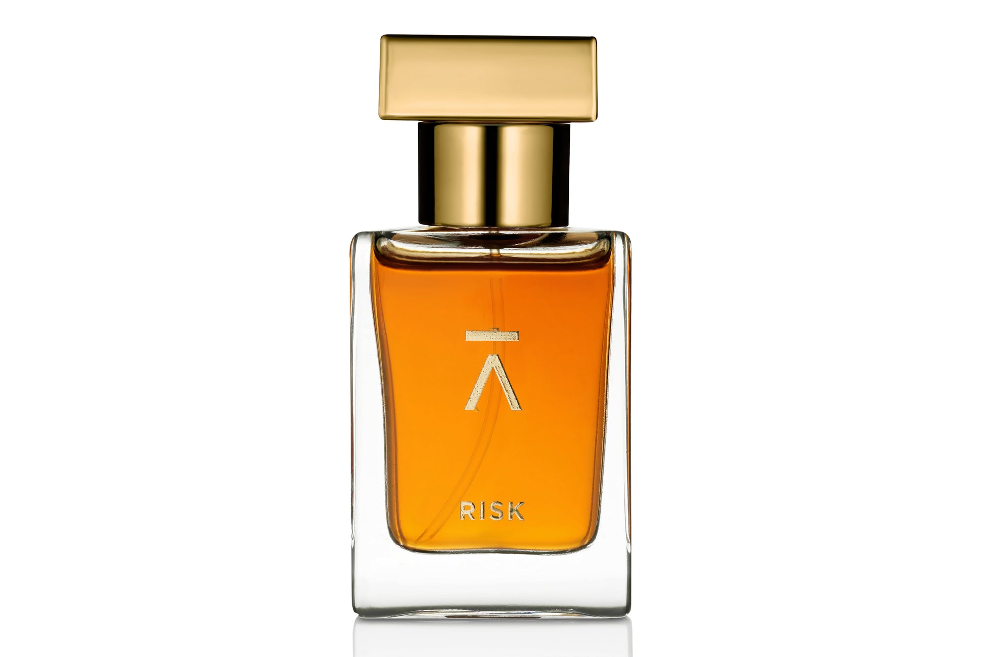 Azman Risk Perfume collaboration with Italian perfumer Antonio Gardoni. Majnoon bottle features a long neck, hand-polished bottle with a heavy gold metal cap. The packaging includes a side-opening heavy cardboard box adorned with a gold foil Azman logo. The studio shot of the Risk perfume bottle is set against a white color background. The whisky gold color of the Risk perfume adds a touch of luxury and sophistication