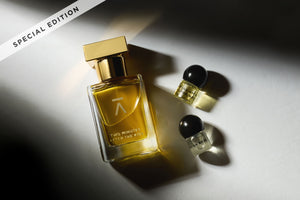 Studio-shot image of Azman Perfumes Special Edition, crafted by Zoologist Bee Perfumer Cristiano Canali. The 30ml bottle, against a dark background, features warm green liquid and a slender design reminiscent of a runway model's long neck. The bottle is adorned with a luxurious heavy gold metallic cap, enhancing its allure. Additionally, the perfume includes 1g oil vials of Mysore Sandalwood oil and Turkish Rose oil
