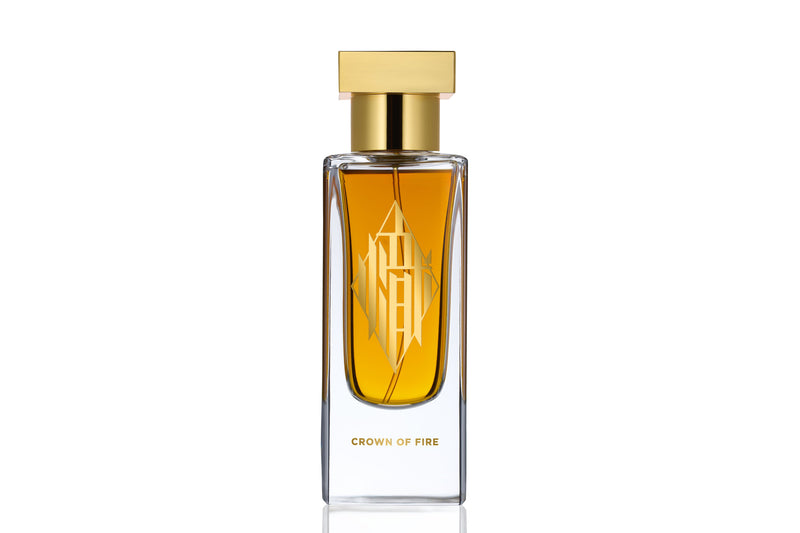Perfume bottle labeled “Crown of Fire” with a gold cap, photographed on a white background. The bottle features elegant Chinese calligraphy in 24 carat gold that translates to “fire.”