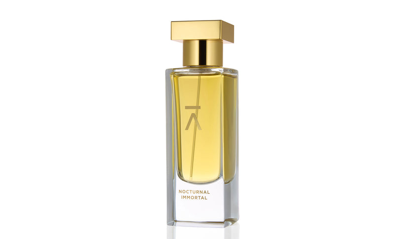 Studio photograph of the ‘Nocturnal Immortal’ perfume bottle by Azman Perfumes, created in collaboration with Julien Rasquinet. Set against a white background, the bottle reflects a woody, oriental, and mysterious aesthetic. The perfume features key notes of Fir Balsam Absolute, Orange Bitter Oil, Cistus Labdanum, Vetiver Oil Haiti, and Hay Absolute, embodying a rich and natural essence.